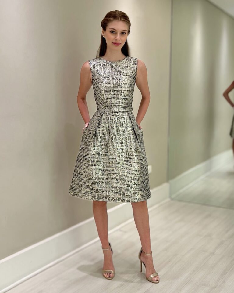 Vestido sem mangas em tweed preto e dourado, com cinto na cintura, saia evasê e bolsos laterais