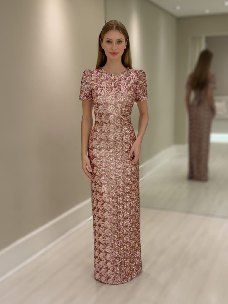 Modelo usando vestido longo de festa com estampa geométrica em tons de rosa e dourado