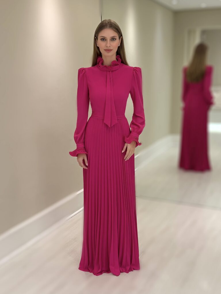 Vestido longo pink em crepe com saia plissada, gola alta com laço e mangas longas bufantes