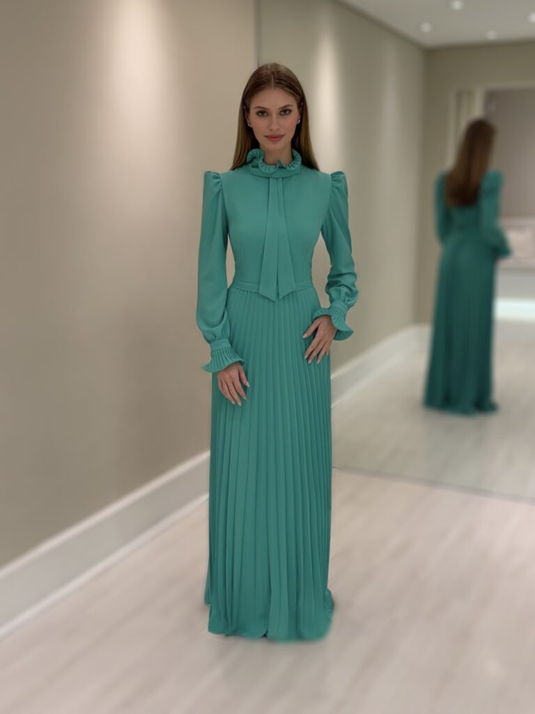 Vestido longo verde em crepe com saia plissada, gola alta com laço e mangas longas bufantes