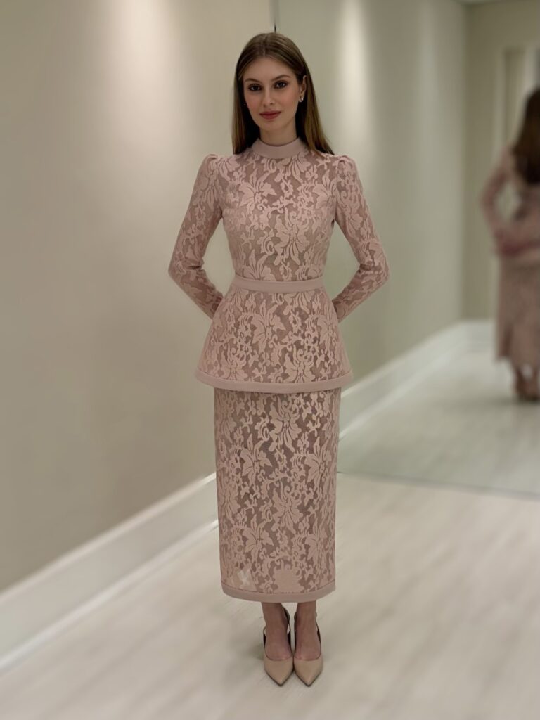 Vestido midi de renda nude com gola alta, mangas longas e basque opcional marcando a cintura